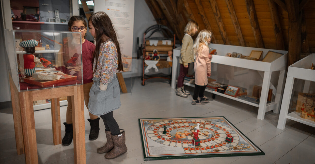 Twee meisjes kijken in de tentoonstelling Spelen met het Verleden naar een vitrine.