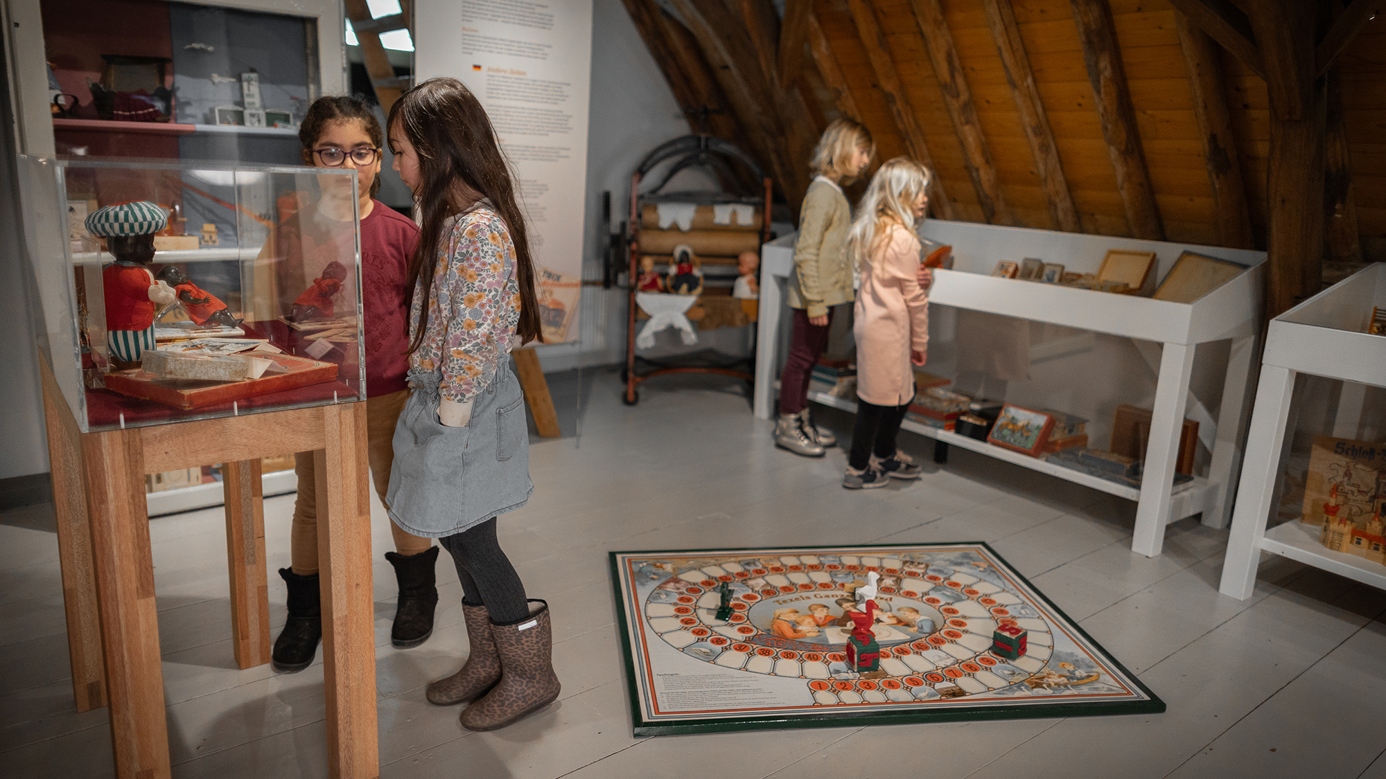 Twee meisjes kijken in de tentoonstelling Spelen met het Verleden naar een vitrine.