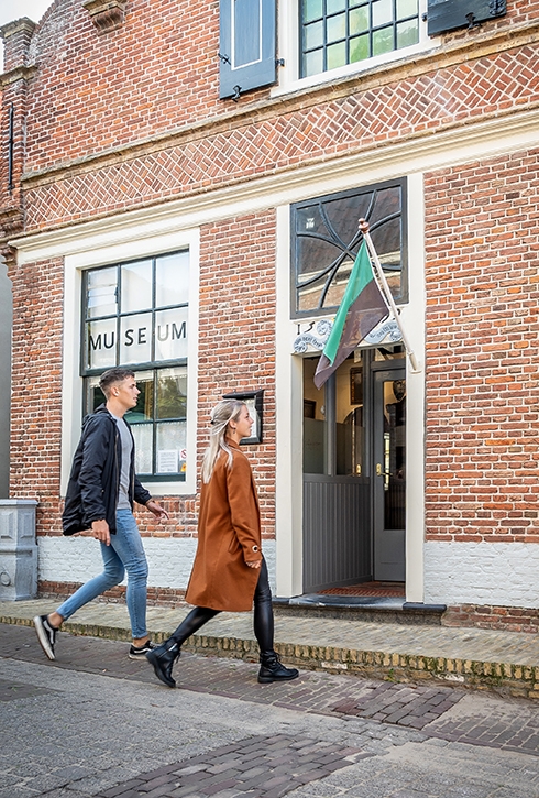 Twee jonge mensen lopen de openstaande deur van de Oudheidkamer binnen.