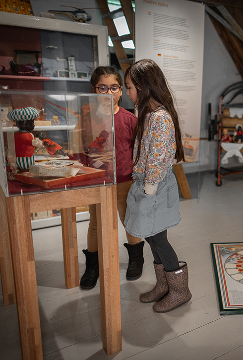 Twee meisjes kijken in de tentoonstelling Spelen met het Verleden naar een vitrine.